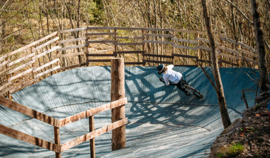 Bilden visar en kvinnlig cyklist som cyklar nedför en ramp sedd snett bakifrån
