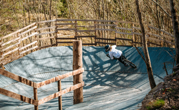 Bilden visar en kvinnlig cyklist som cyklar nedför en ramp sedd snett bakifrån