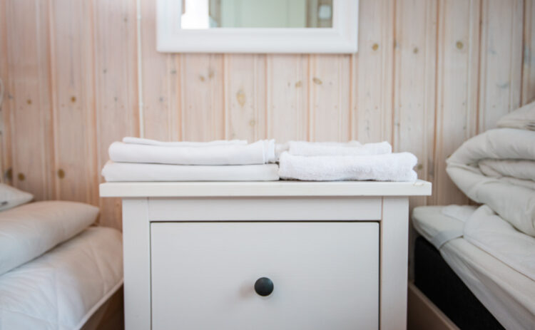 Bild på sängbord med lakan och handdukar i Flottbros stugby nära Stockholm.