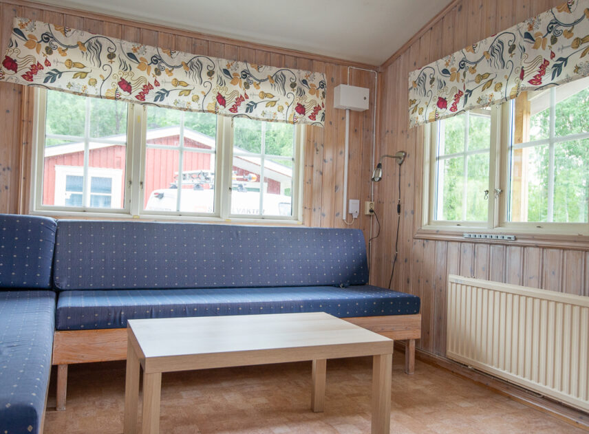 Bild på interiör av stuga med soffa.