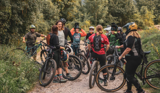 Bild på en grupp tjejer med cyklar och full utrustning som pausar i skogen