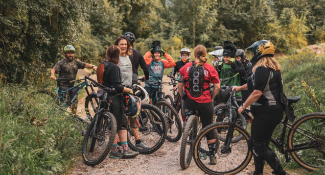 Bild på en grupp tjejer med cyklar och full utrustning som pausar i skogen