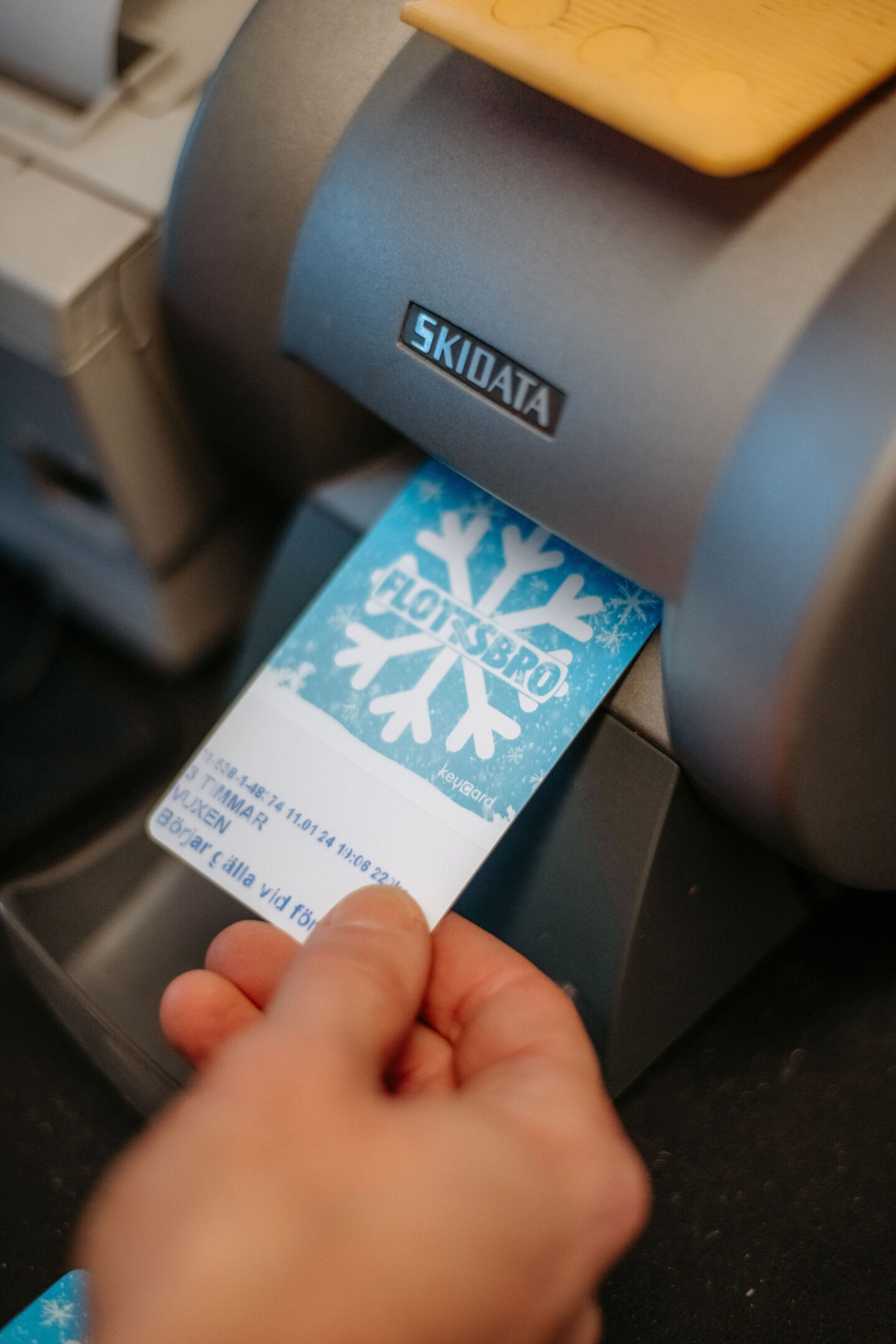 Bilden visar en hand som håller i ett skipass instucken i en kortskrivare.