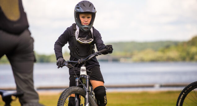 En ungdom tränar balans på cykel, i bakgrunden syns en sjö.