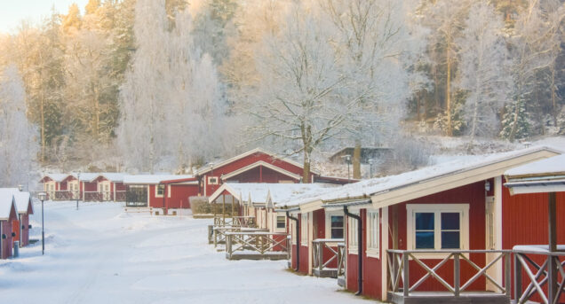 Stugor på Flottsbros camping på vintern med snö och vita träd.