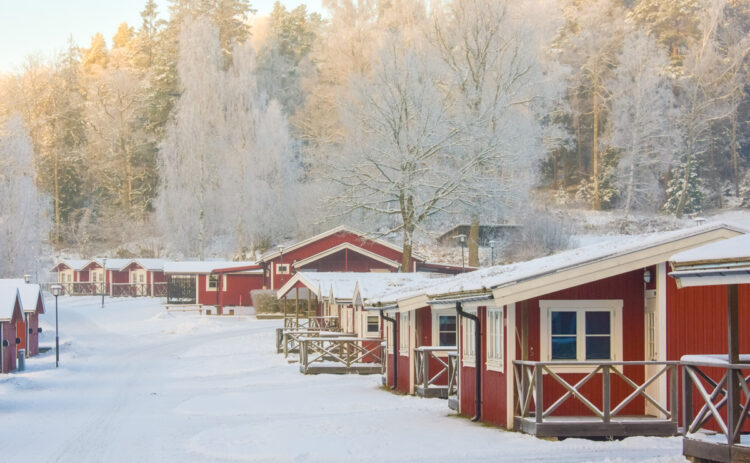 Stugor på Flottsbros camping på vintern med snö och vita träd.