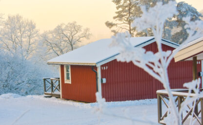 Stugor på Flottsbros camping på vintern med snö och vita träd.