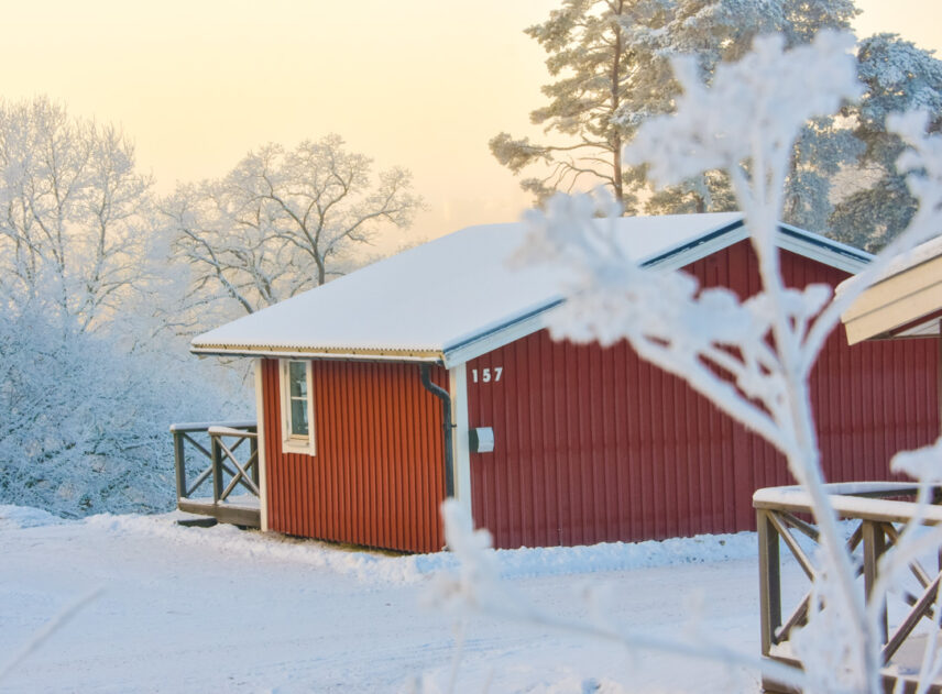 Stugor på Flottsbros camping på vintern med snö och vita träd.