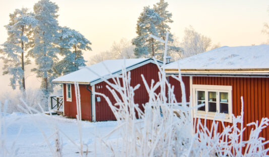 Stugor på Flottsbros camping på vintern med snö och vita träd.