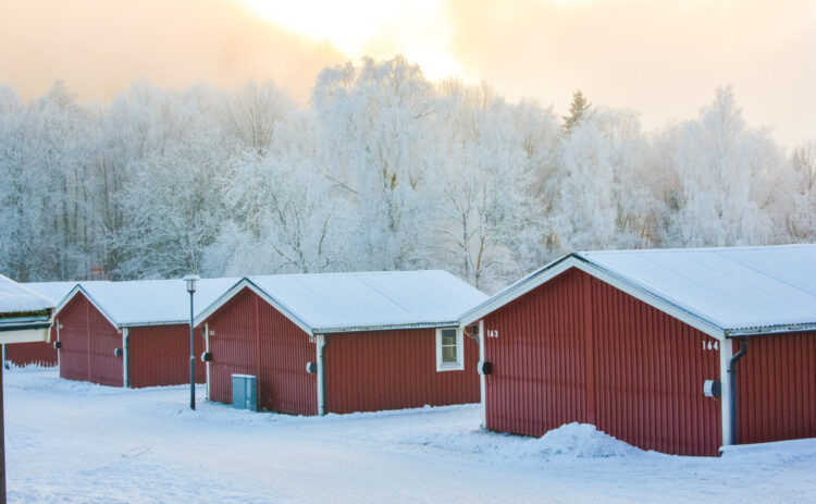 Stugor på Flottsbros camping på vintern med snö och vita träd.