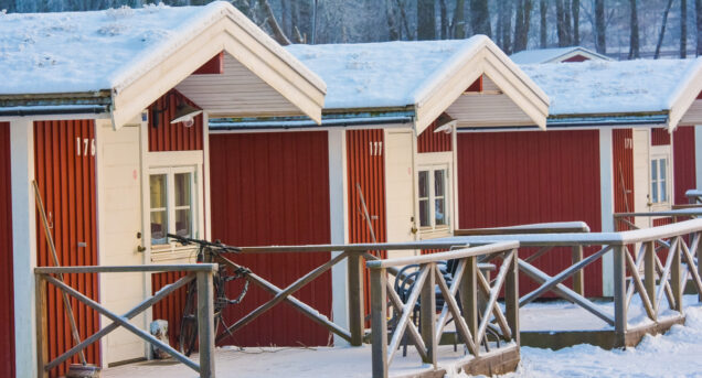Stugor på Flottsbros camping på vintern med snö och vita träd.