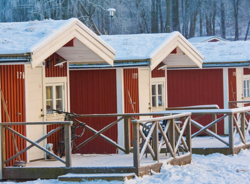 Stugor på Flottsbros camping på vintern med snö och vita träd.