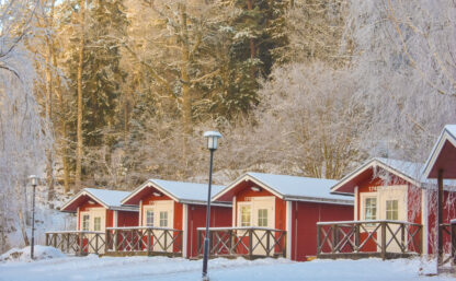 Stugor på Flottsbros camping på vintern med snö och vita träd.