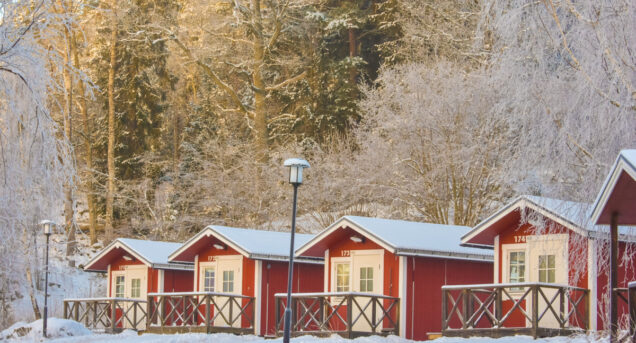 Stugor på Flottsbros camping på vintern med snö och vita träd.