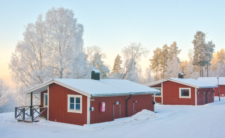 Stugor på Flottsbros camping på vintern med snö och vita träd.