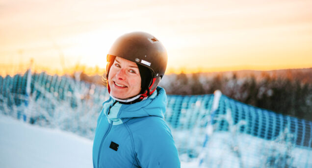 Porträtt på en kvinna i skidbacken en solig vinterdag.