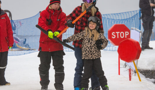 Bild på på två personer som får hjälp med skidlift av liftskötare.