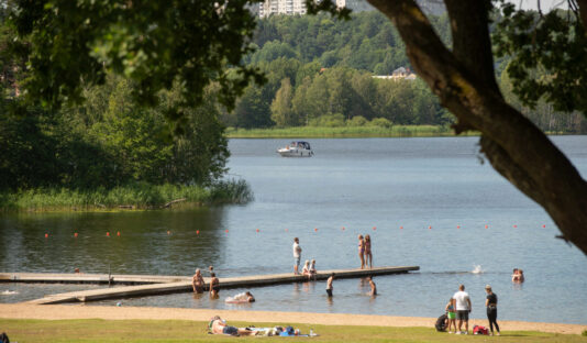 Bild på Flottsbro badstand en solig sommardag, i bilden finns en grupp personer som står på bryggan.