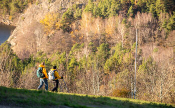 Två personer vandrar ner för Flottsbros topp en solig höstdag.