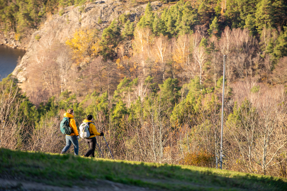 Två personer som vandrar ner för Flottsbros topp en solig höstdag.