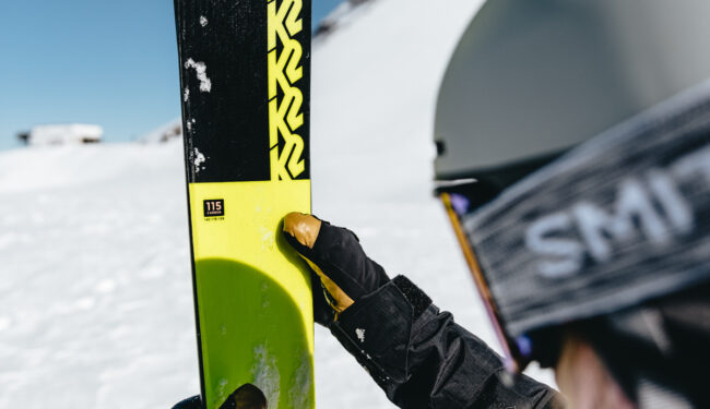 Närbild på skidåkare som hjåller skidor sedd bakifrån.