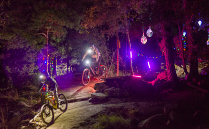 Ungdomar cyklar i en upplyst Bike Park i höstmörkret.