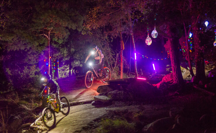 Ungdomar cyklar i en upplyst Bike Park i höstmörkret.