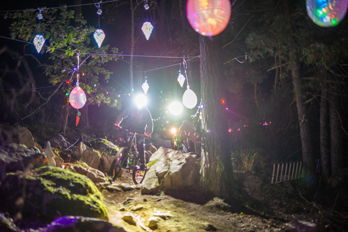 Cyklister i en Bike Park som lysts upp med färgglada lampor i höstmörkret. 