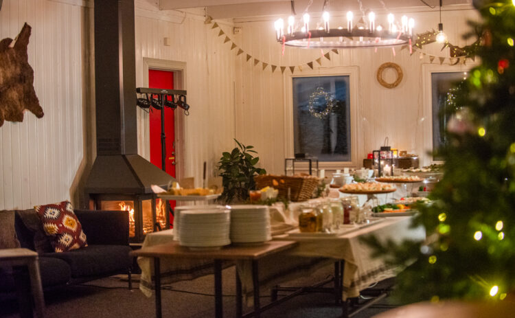 Bild på ett rum med braskamin och julgran samt ett uppdukat julbord.
