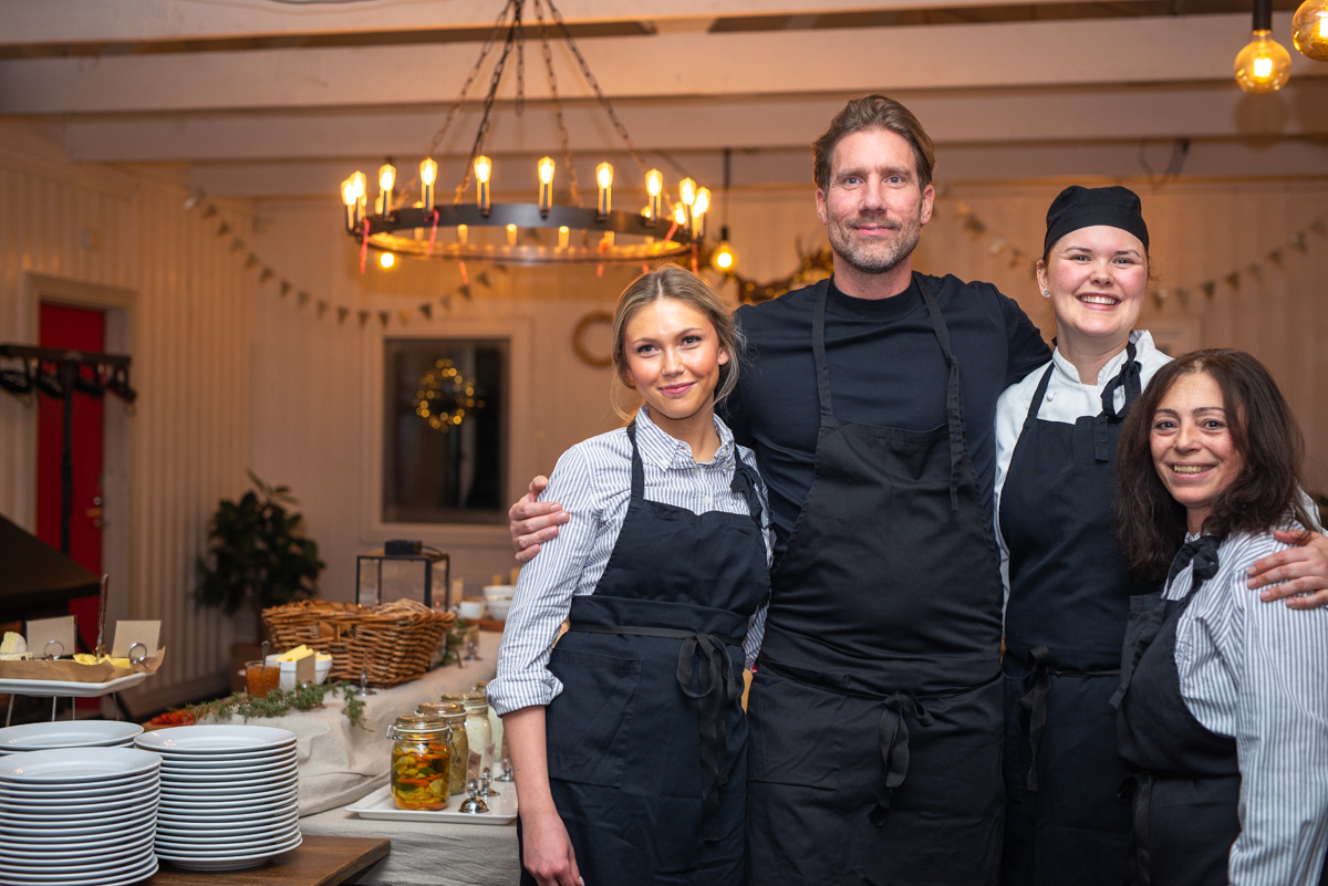 En porträttbild på Värdshusets medarbetare tagen framför ett uppdukat julbord.