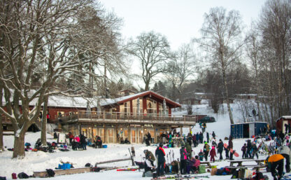 Flottbros värdshus och skidhyra på vintern, i förgrunden syns en grupp människor och skidställ med utrustning.