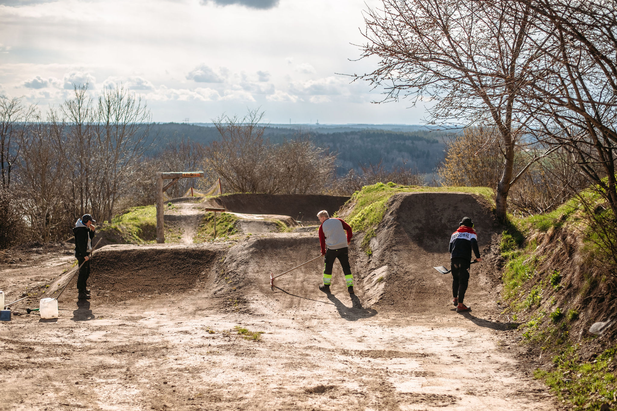 Bilden visar 2 personer som gräver framför 2 stora hopp i Flottsbro Bike Park.