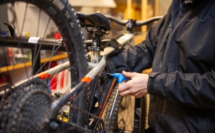 Närbild på händer av en mekaniker som mekar med en cykel.