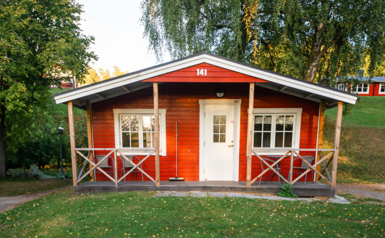 Bild på röd stuga sedd rakt framifrån.
