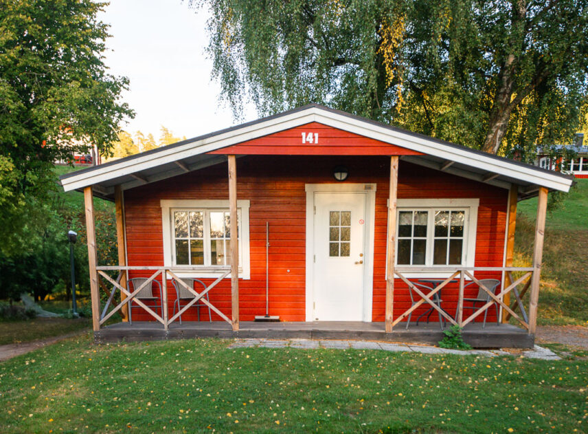 Bild på röd stuga sedd rakt framifrån.