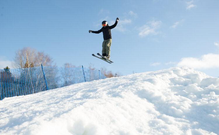 Bild på en ungdom som hoppar i Parken mot blå himmel, i förgrunden syns ett stort hopp.