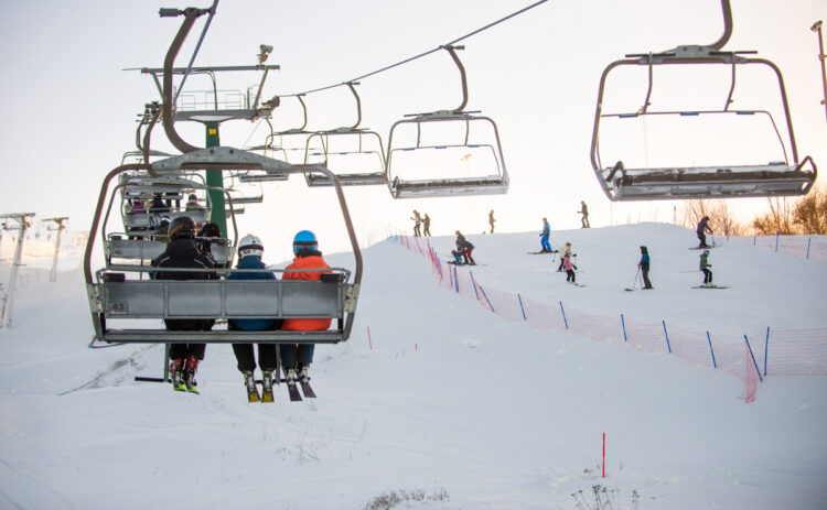 Bild på korgliften med vy över backen, i liften sitter tre personer.