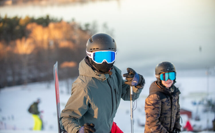Bilden visar två barn som står i backen och ser mot kameran i bakgrunden syns sjön.