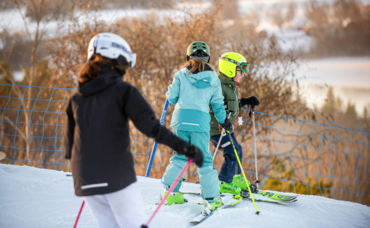 Bilden visar tre barn som åker skidor i backen