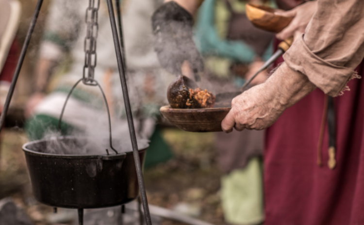 Bild på en kittel och ett par händer som håller ett matkärl.