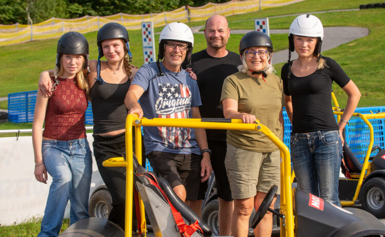 Porträtt på 6 personer med hjälmar som står bakom en Gokart.