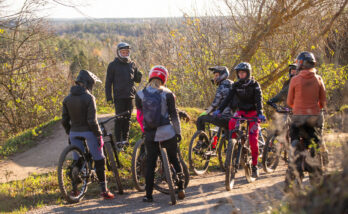 5 cyklister sedda bakifrån med en ledare sedd bakifrån ståendes på en höjd
