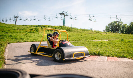 En kvinna kör en Downhill Car ner för en backe under sommaren.