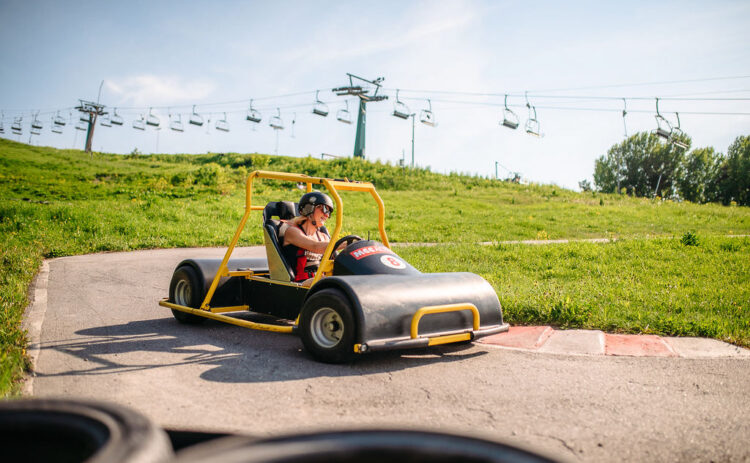En kvinna kör en Downhill Car ner för en backe under sommaren.