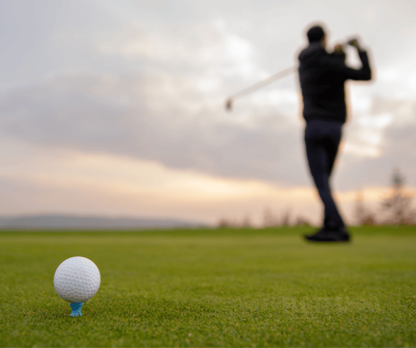 close up image of a golf ball with a player in siluett in the background