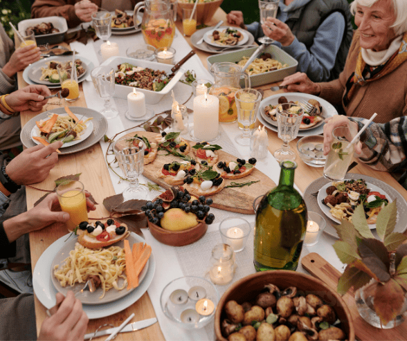 The image shows a set table with delicious food and hands that are reaching for it. 