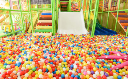 Närbild på ett bollhav i glada färger, bakgrunden syns lekställningar i ljusgrönt.