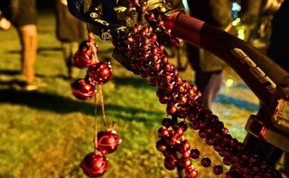 En röd pärlgirlang virad runt en bromsvajer på en cykel.
