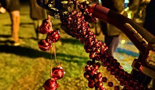 En röd pärlgirlang virad runt en bromsvajer på en cykel.