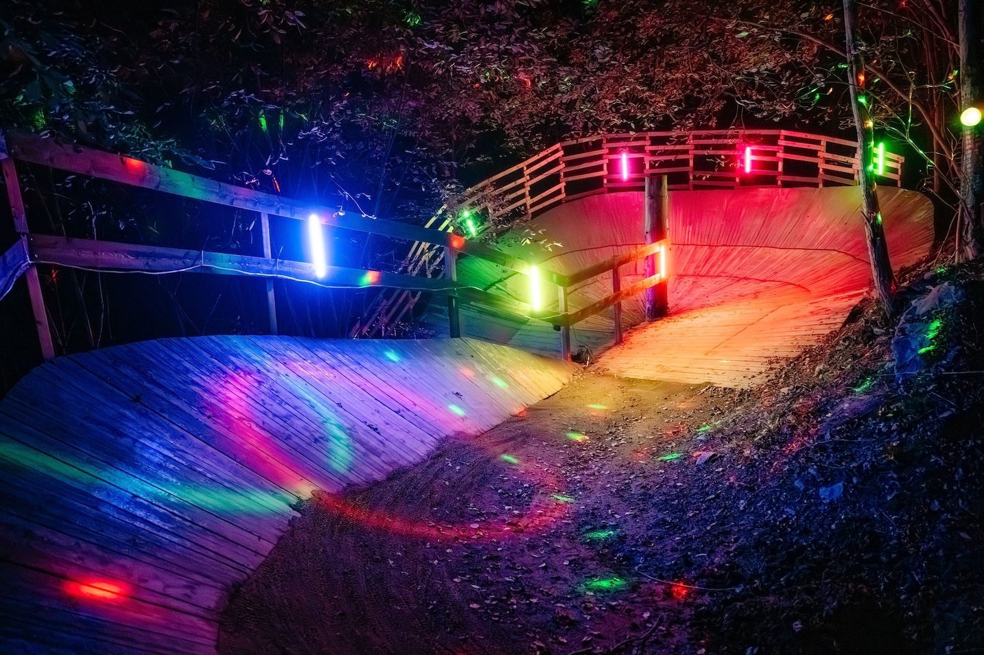 En wallride i en bike park upplyst i färgglada lampor.